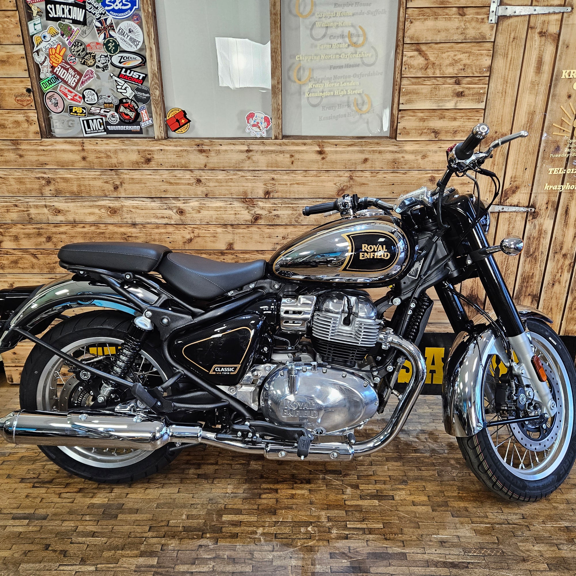 Royal Enfield motorcycle indoors against a wooden wall with decorative elements.