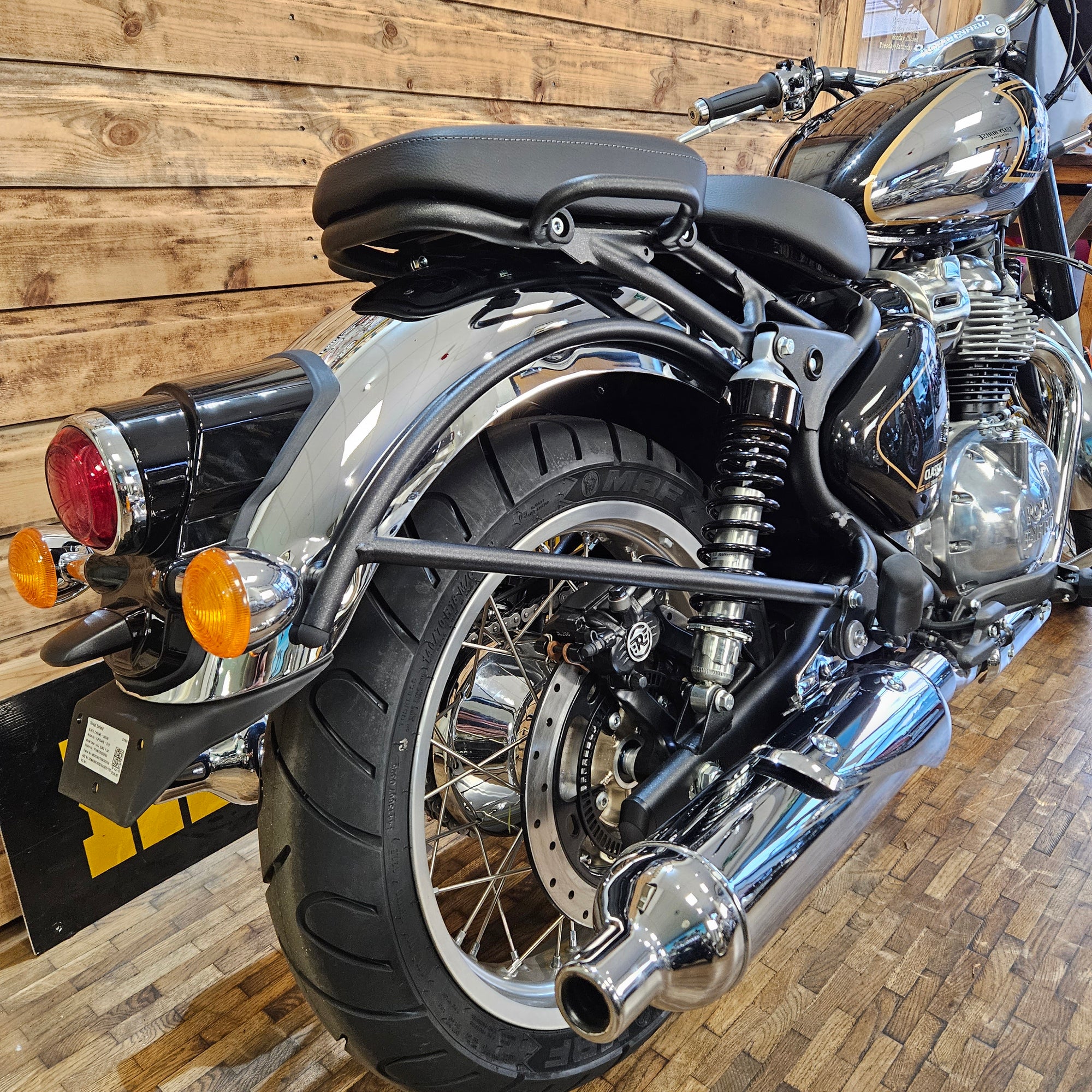 Close-up of a motorcycle's front wheel and suspension system on a wooden floor.