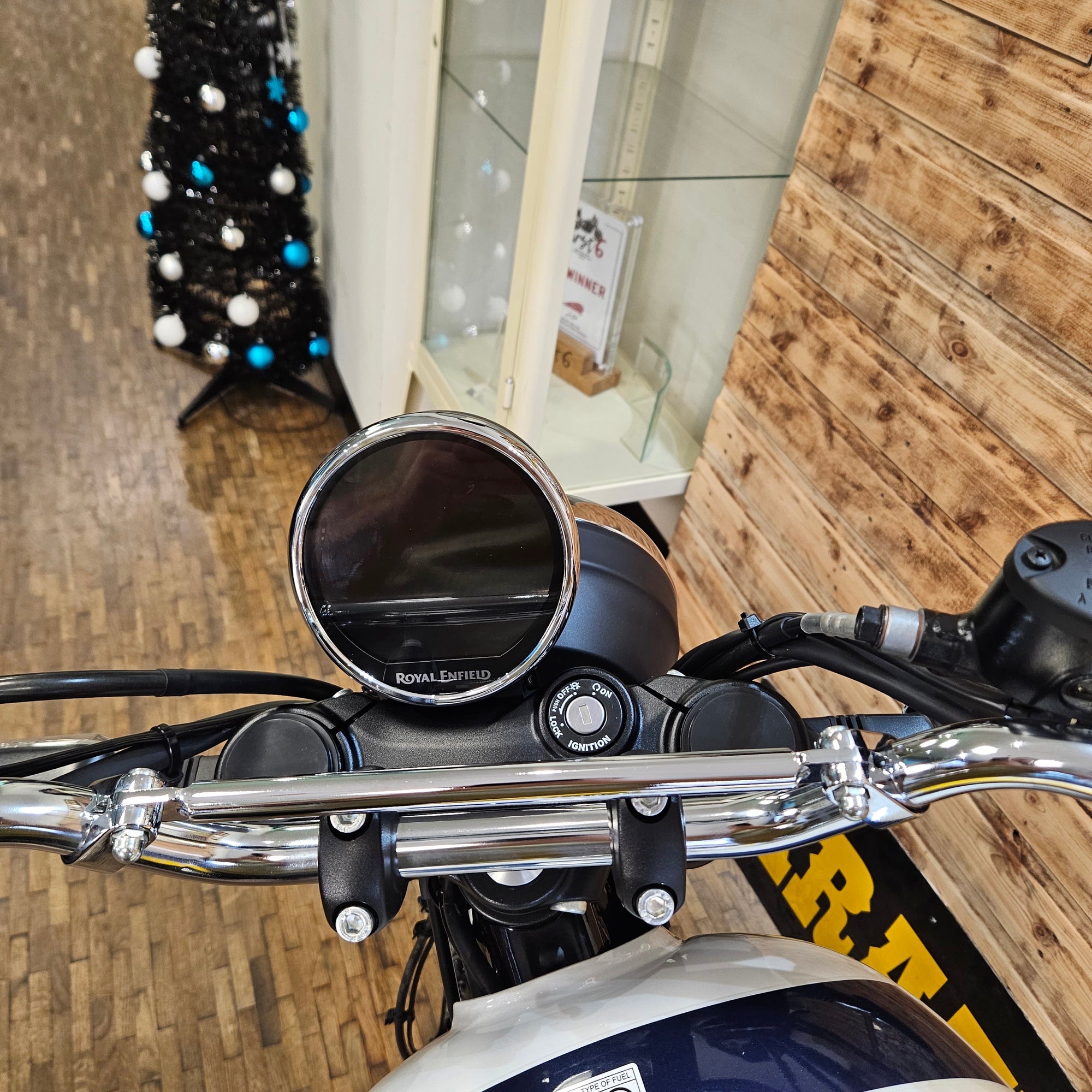 Close-up of a motorcycle handlebar with a wooden wall background