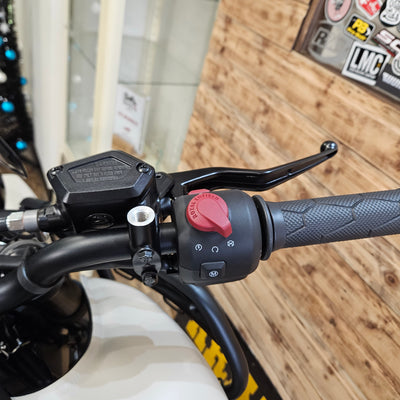 Close-up of a motorcycle handlebar with control buttons on a wooden background