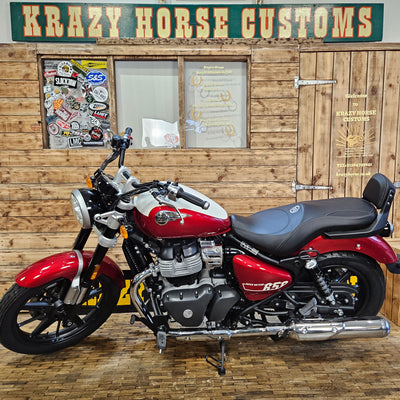 Red motorcycle parked inside a building with wooden walls and a sign.