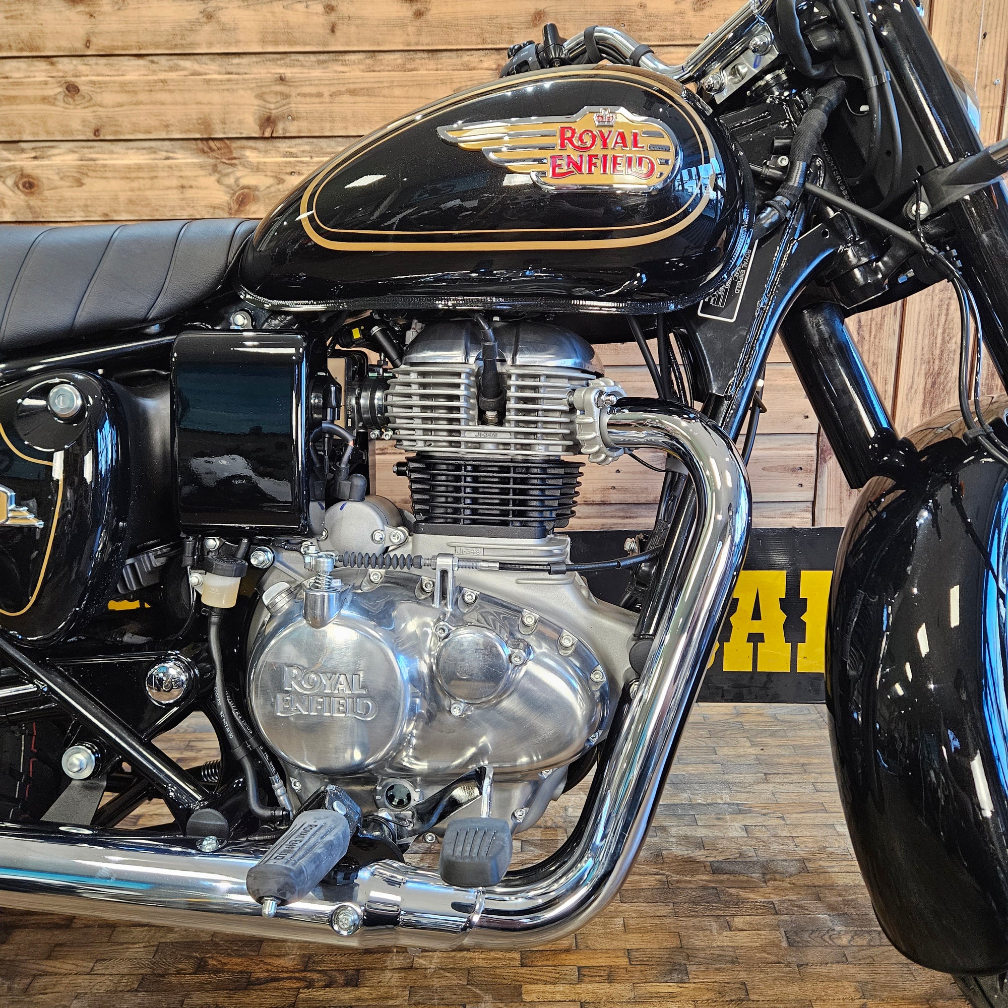 Close-up of a motorcycle engine with 'Royal Enfield' branding against a wooden background.