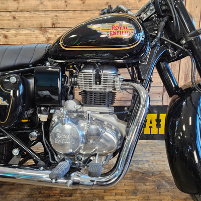 Close-up of a motorcycle engine with 'Royal Enfield' branding against a wooden background.