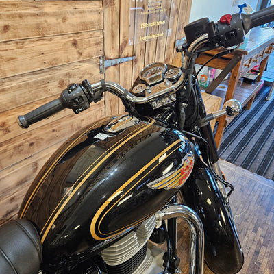 Close-up of a black motorcycle with chrome details on a wooden floor.