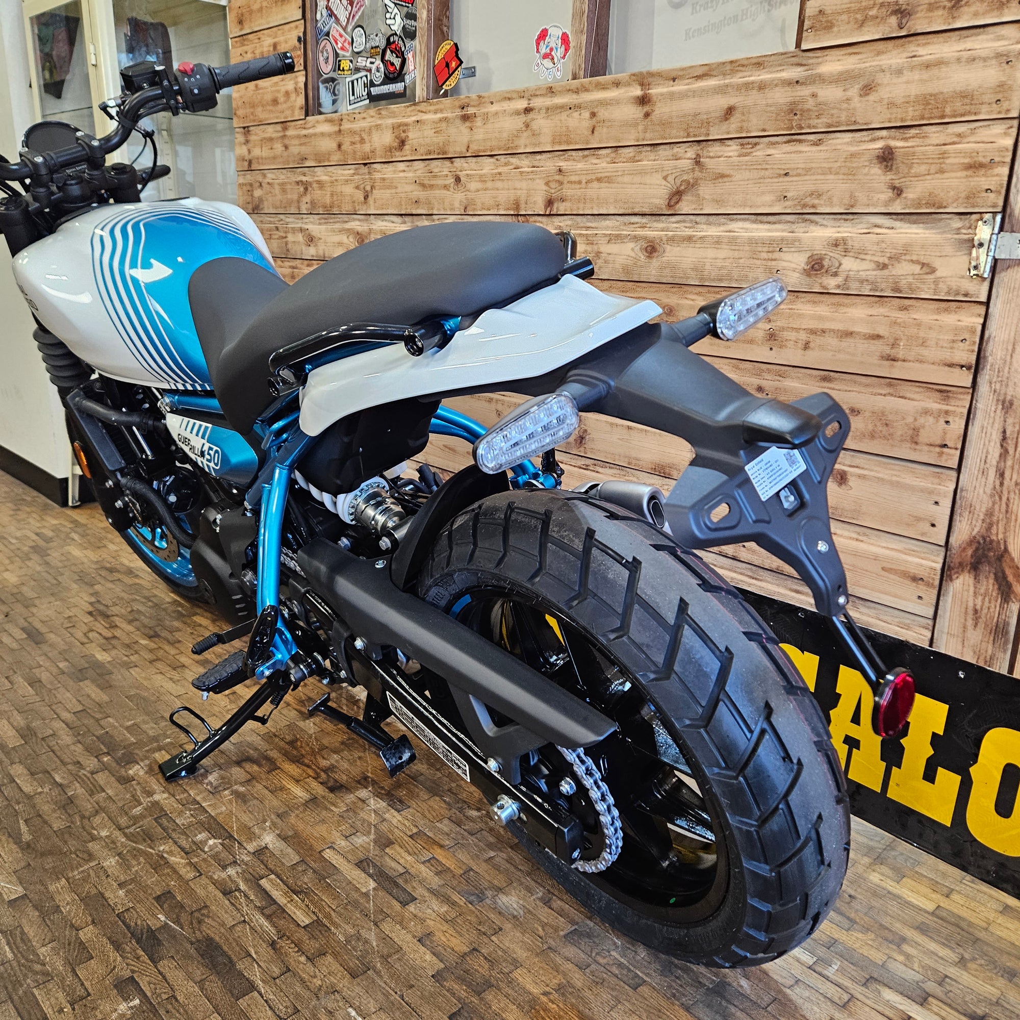 Motorcycle parked indoors with wooden floor and wall in the background