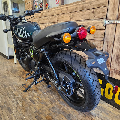 Motorcycle parked indoors with wooden floor and wall in the background