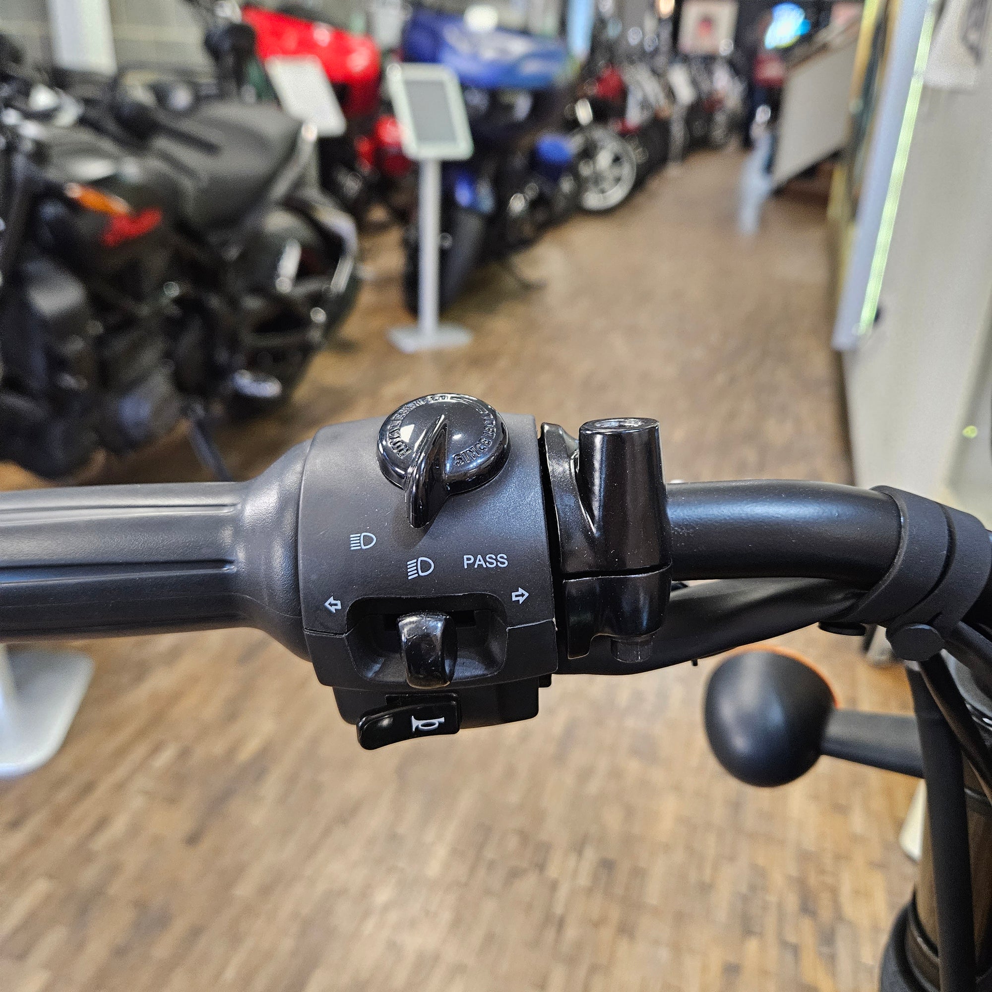 Close-up of a motorcycle handlebar with controls in a showroom setting