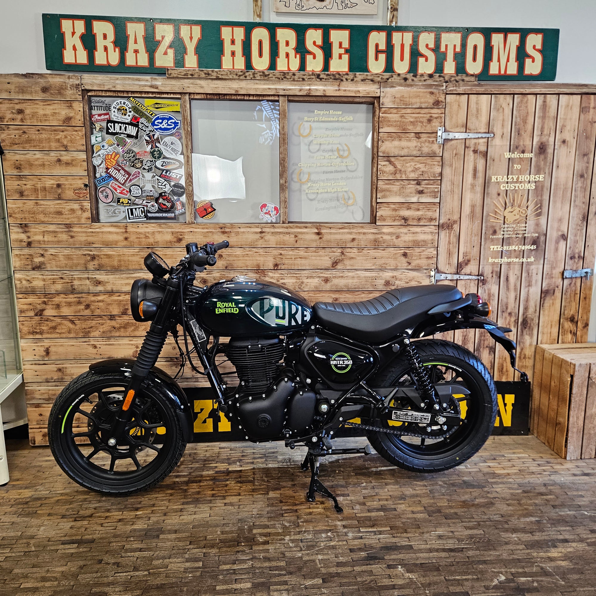 Motorcycle hanging on a wooden wall with 'Krazy Horse Customs' sign.