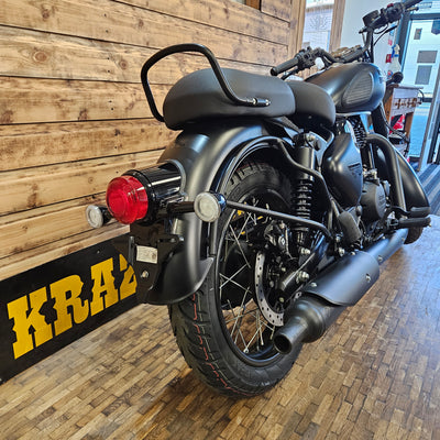 ROYAL ENFIELD CLASSIC 350 - Stealth Black motorcycle on a wooden floor with a brick wall background