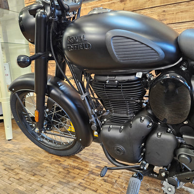 Black Royal Enfield motorcycle on a wooden floor