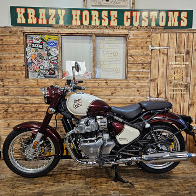 Motorcycle parked against a wooden wall with 'Krazy Horse Customs' sign.