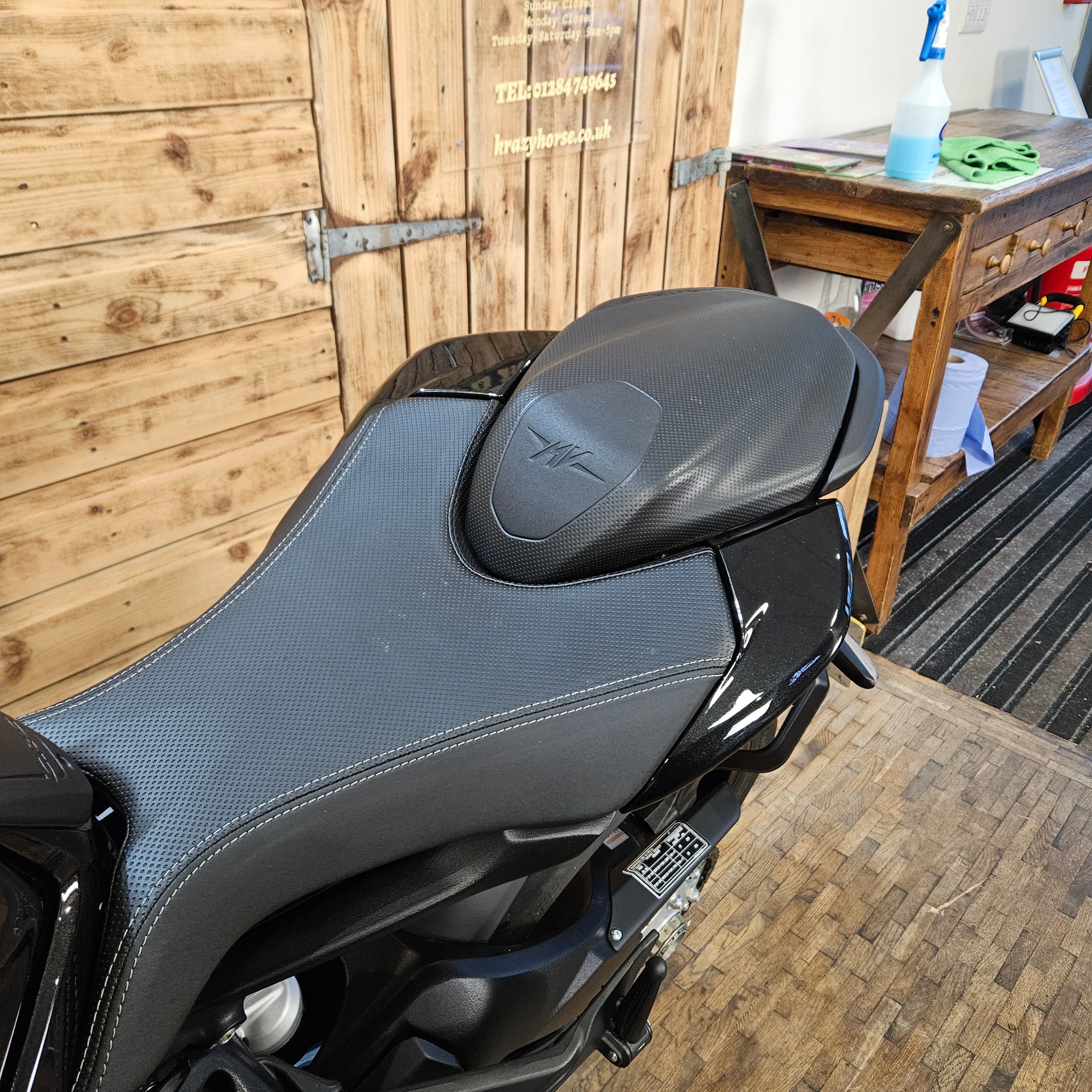 Motorcycle seat on a wooden deck with tools and equipment in the background