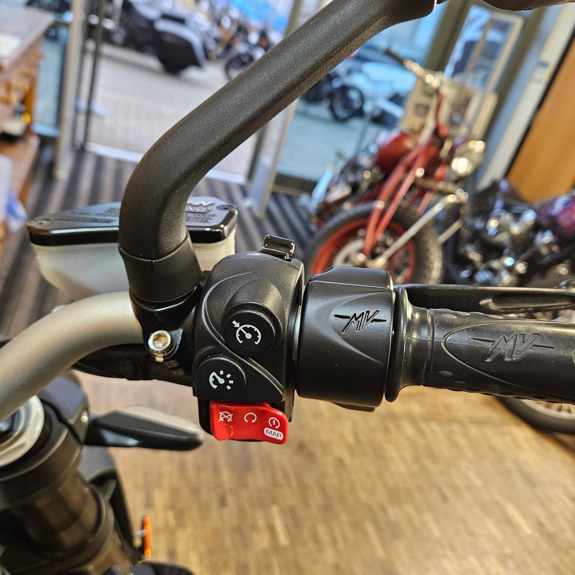 Close-up of a motorcycle handlebar with control buttons in an indoor setting