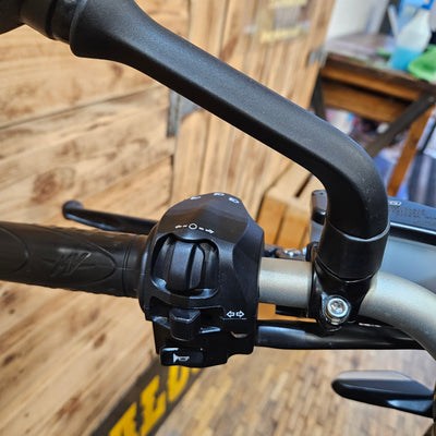 Close-up of a motorcycle handlebar with control buttons on a blurred background
