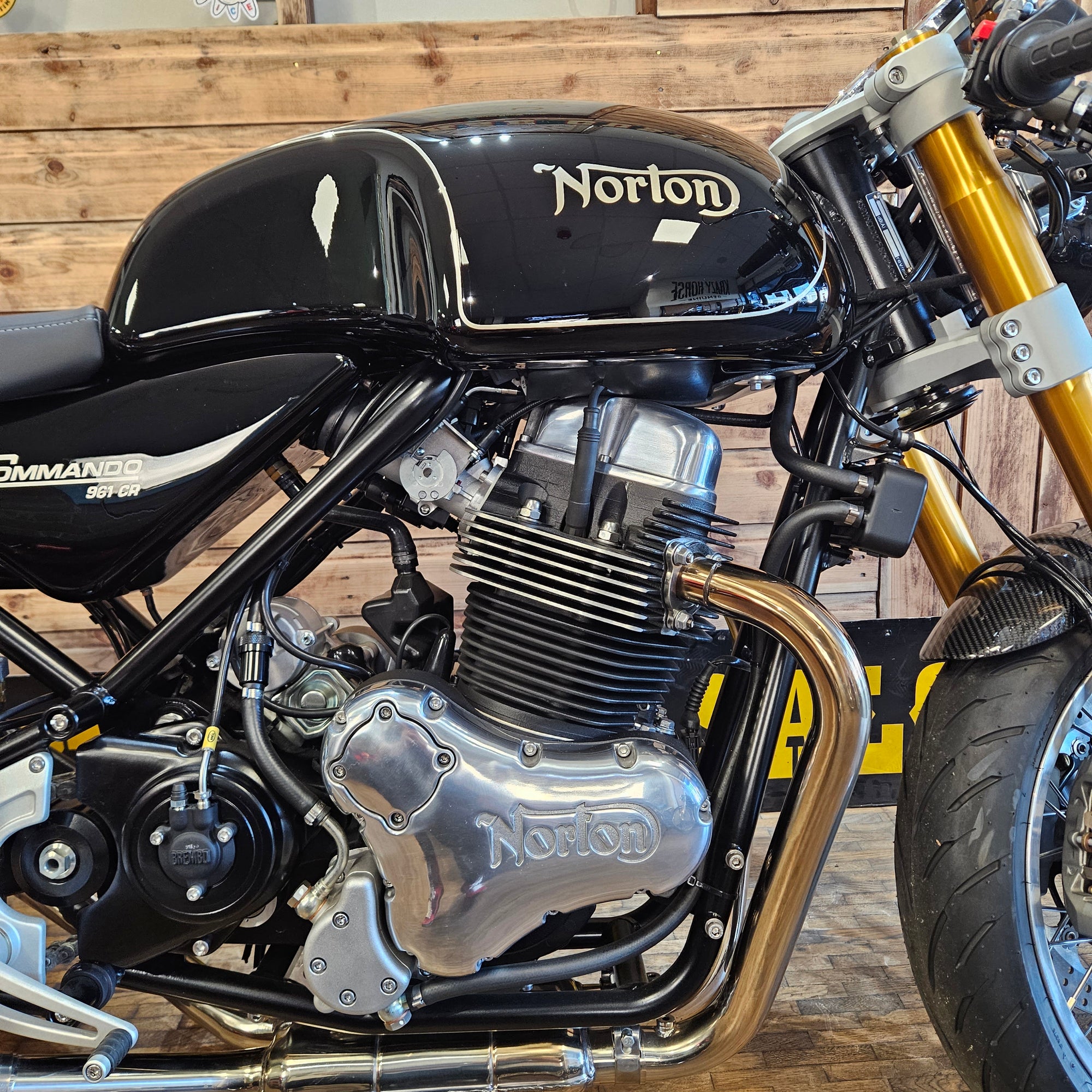 Close-up of a Norton motorcycle engine and exhaust system against a wooden background
