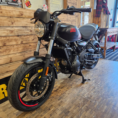 Black motorcycle on a wooden floor with a brick wall background