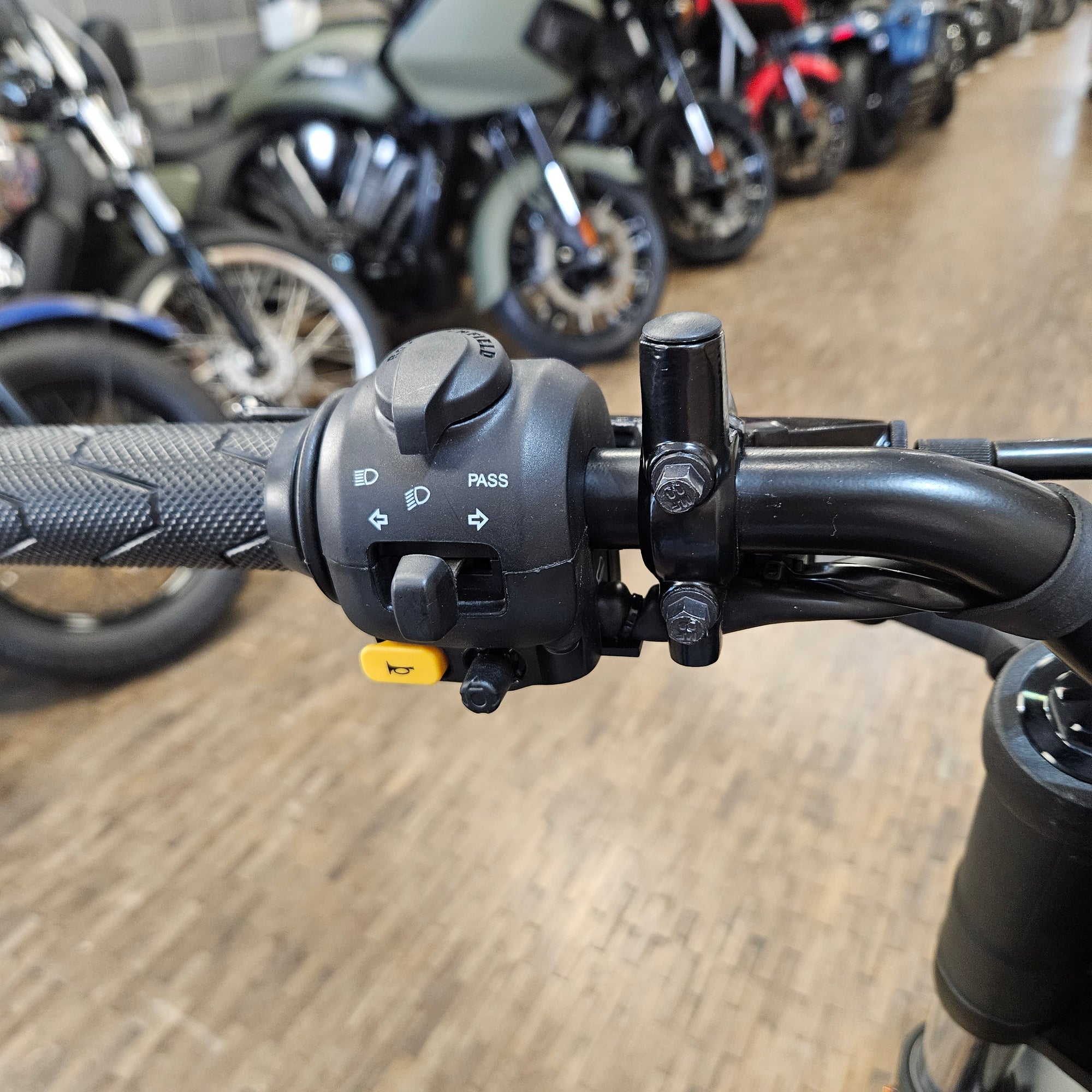 Close-up of a motorcycle handlebar with control buttons on a blurred background