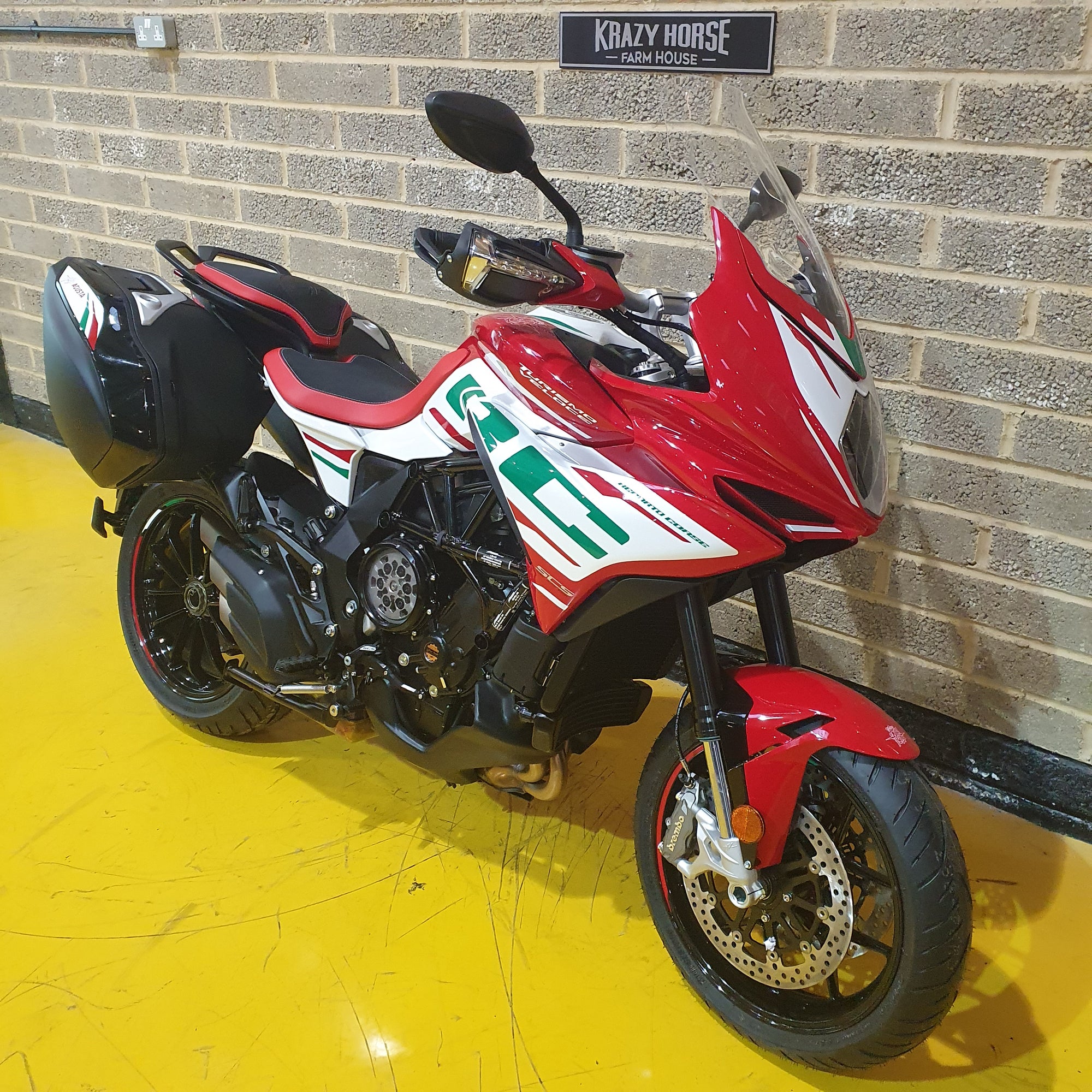 Red and black motorcycle on a yellow floor with a brick wall background