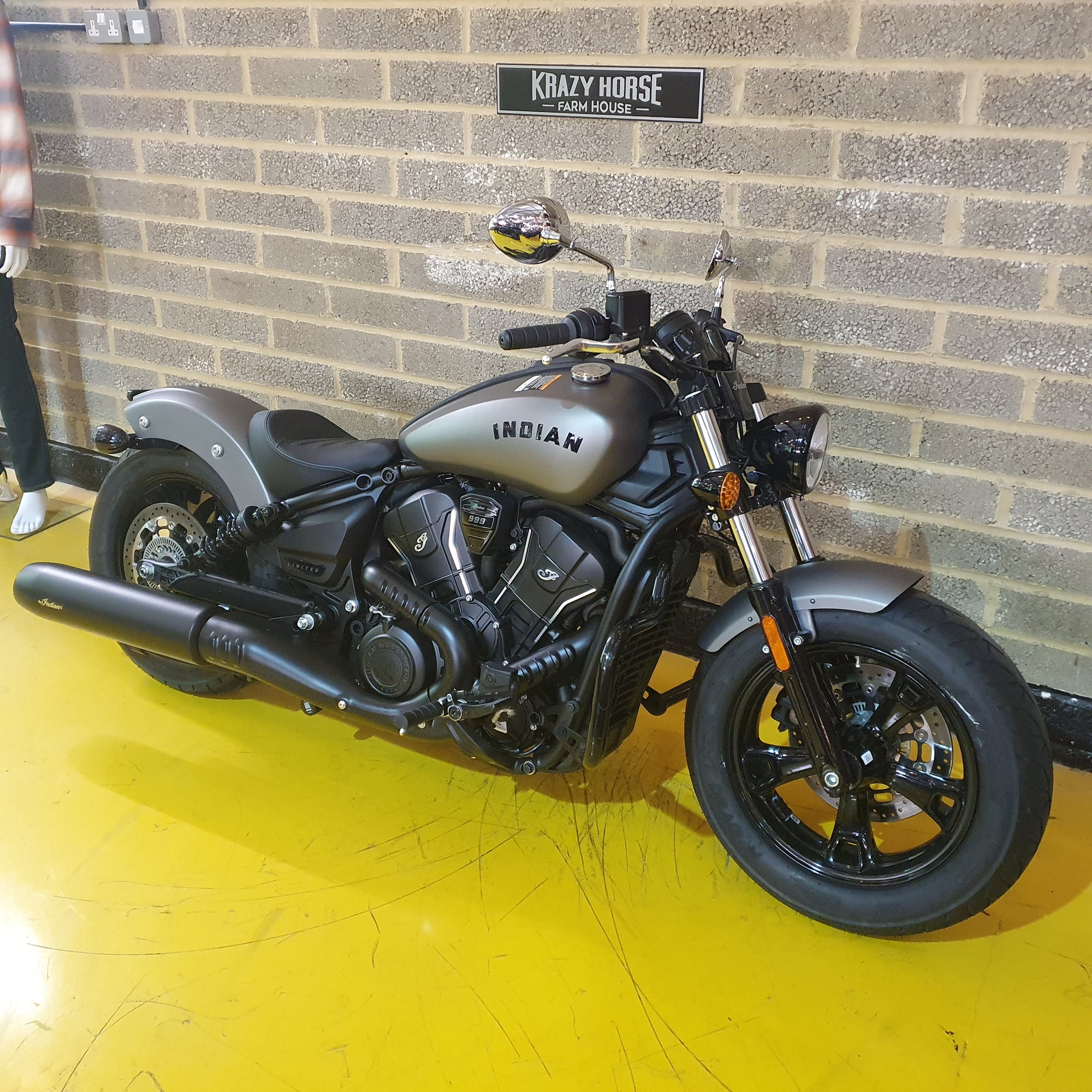 Motorcycle parked against a brick wall with 'Krazy Horse' branding.