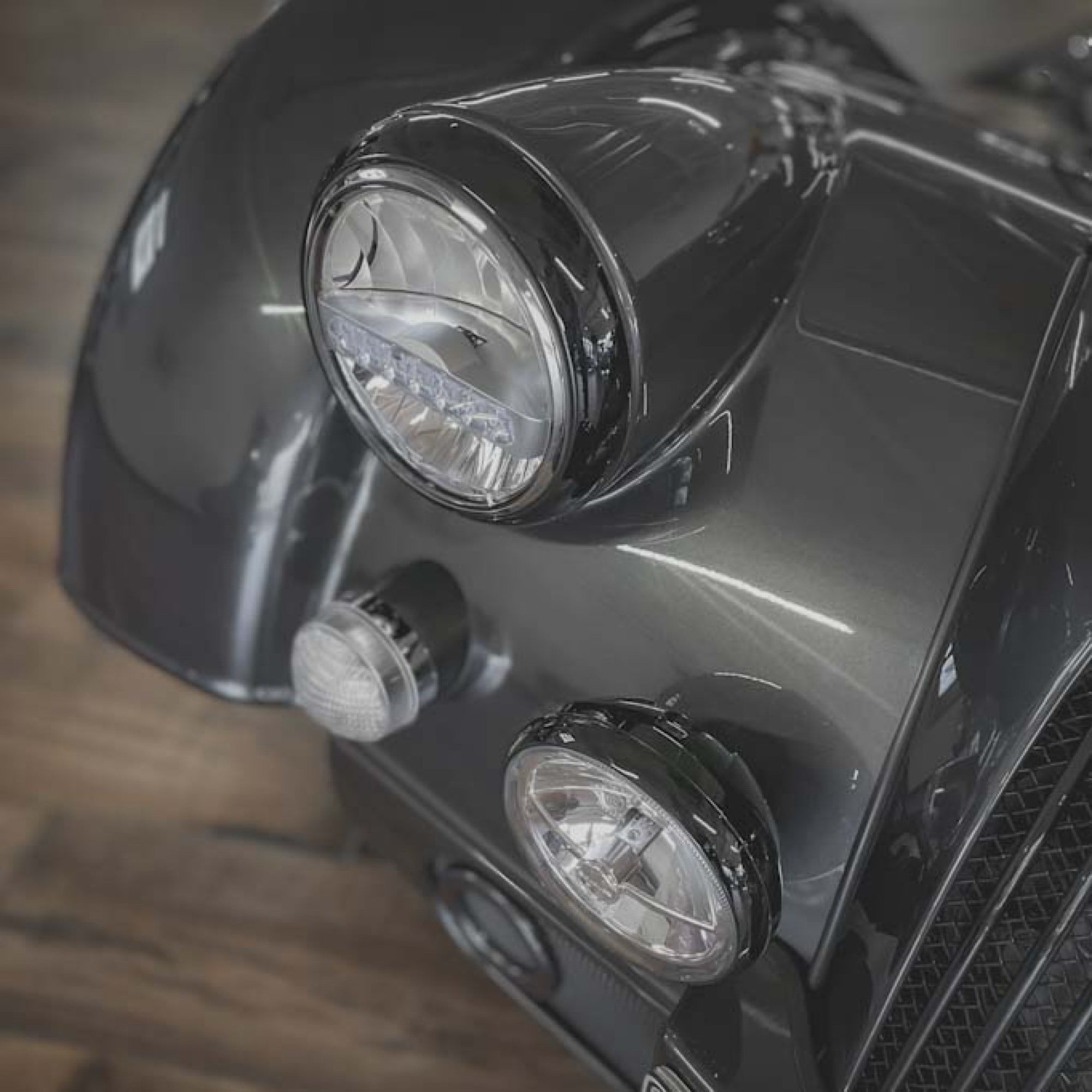 Close-up of a motorcycle's front lights on a wooden floor.
