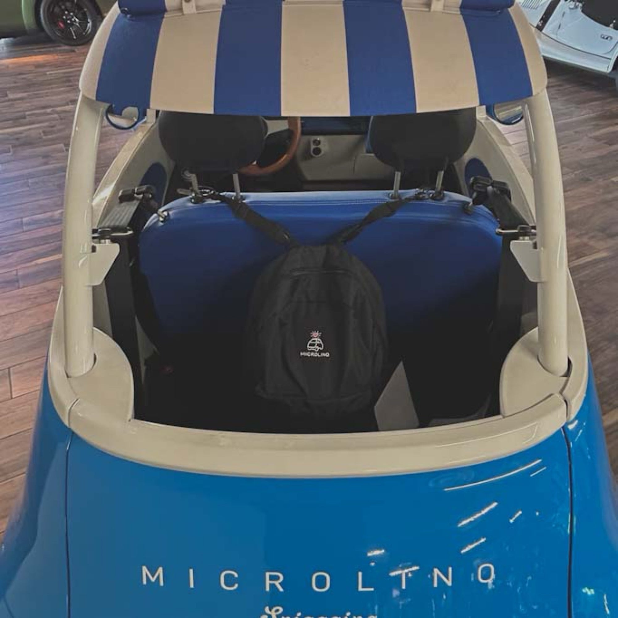 Blue and beige electric vehicle with a striped canopy and a black bag inside, brand 'MICROLINQ' visible.