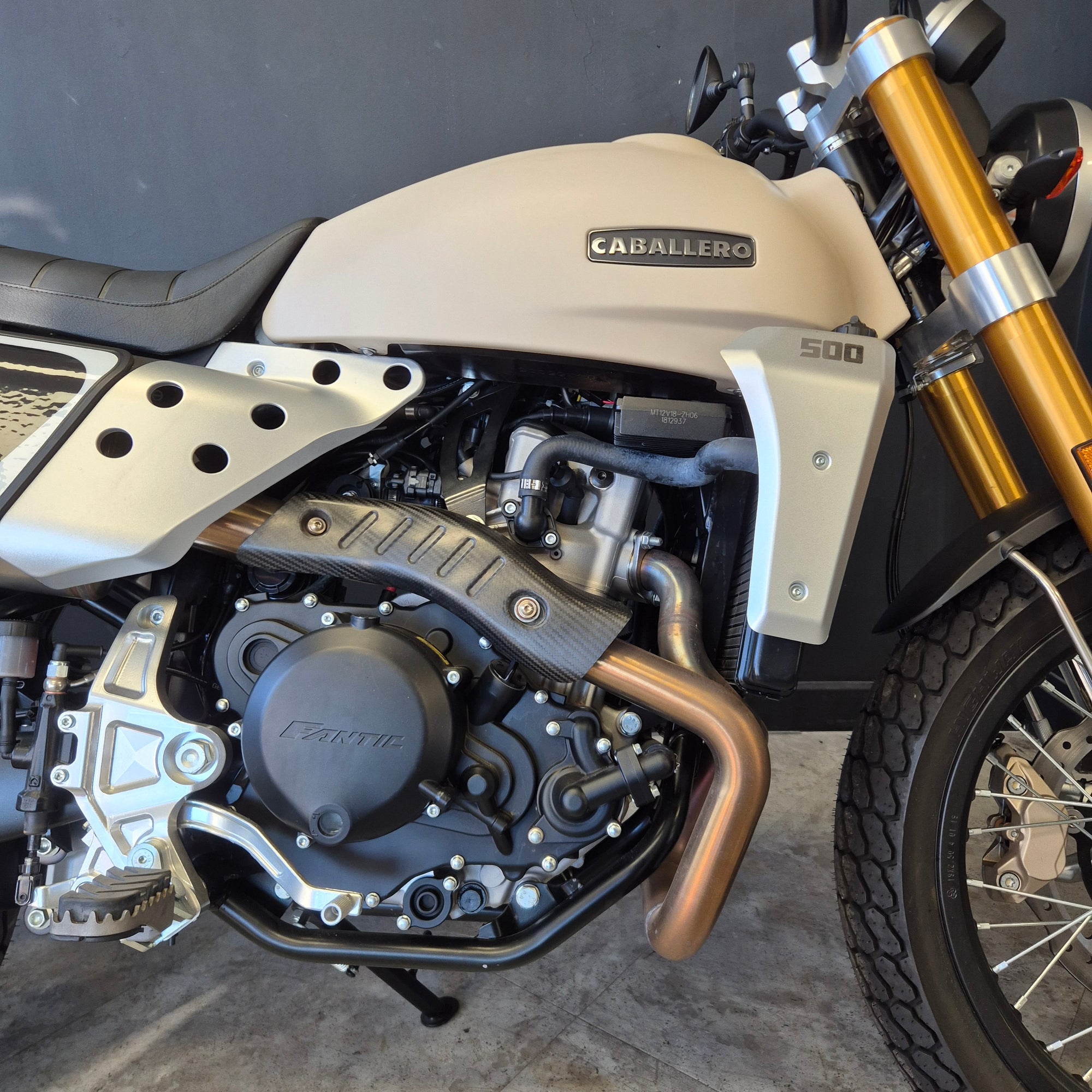 Close-up of a motorcycle engine and exhaust system on a concrete surface.