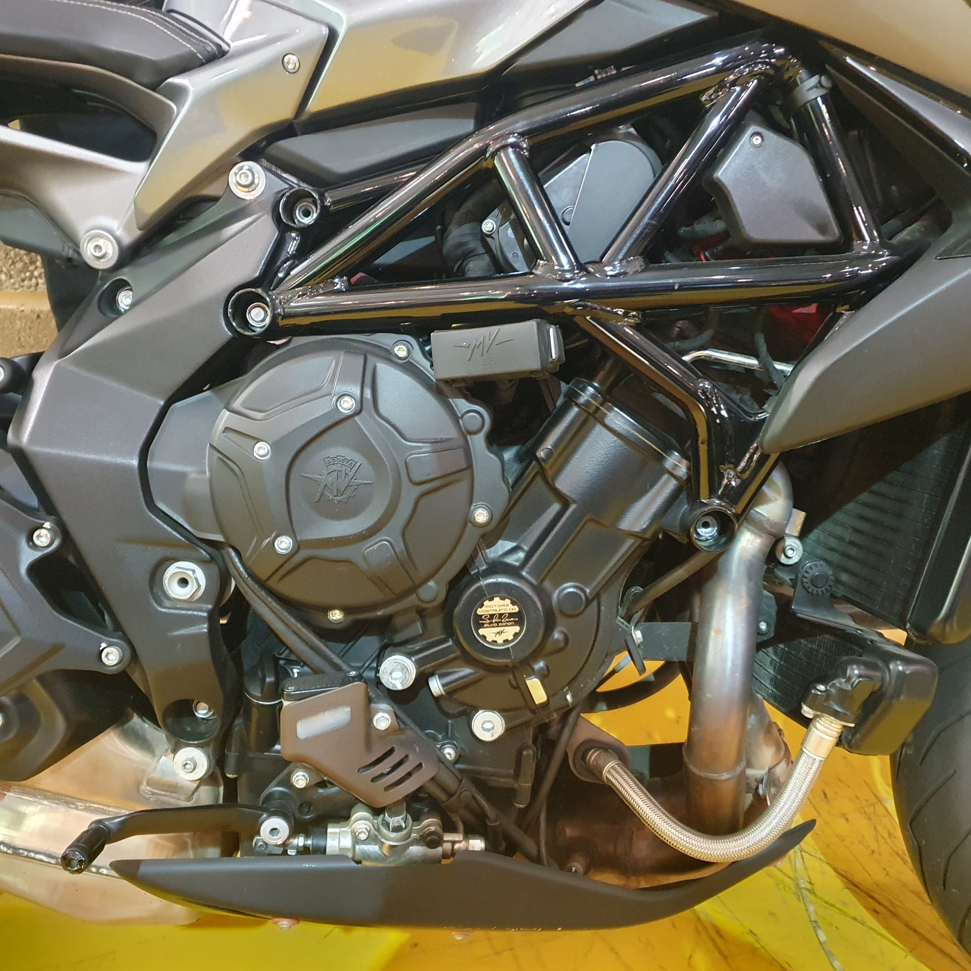 Close-up of a motorcycle engine with visible branding on a yellow background