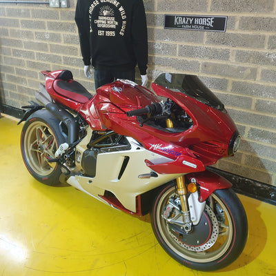 Red and white motorcycle indoors with a person wearing a black hoodie in the background.