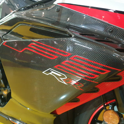 Close-up of a motorcycle with a carbon fiber finish and red branding.
