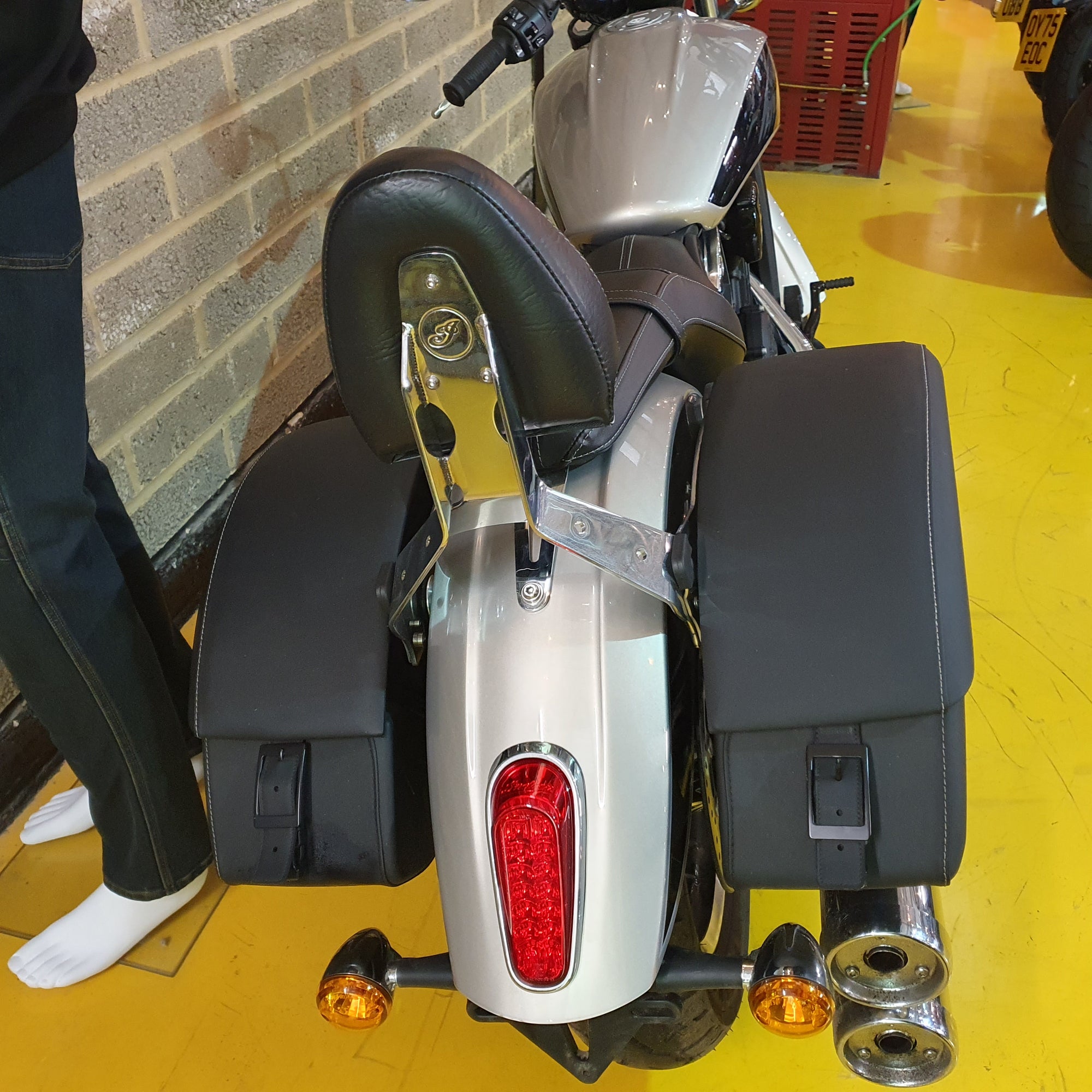Motorcycle with saddlebags on a yellow floor against a brick wall.