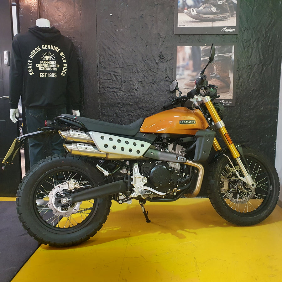 Orange and black motorcycle on display with a person wearing a branded hoodie in the background.