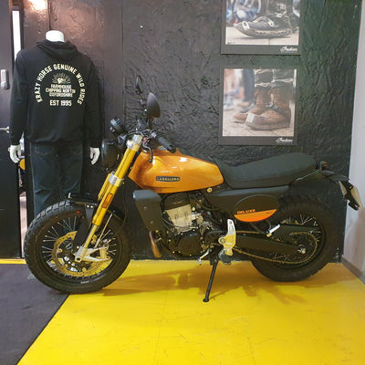 Motorcycle on display with a black wall and posters in the background