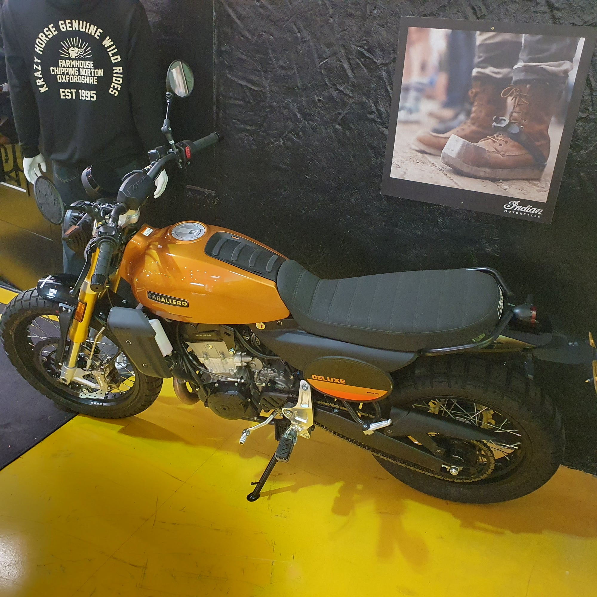Orange and black motorcycle on a yellow floor with a dark textured wall in the background.