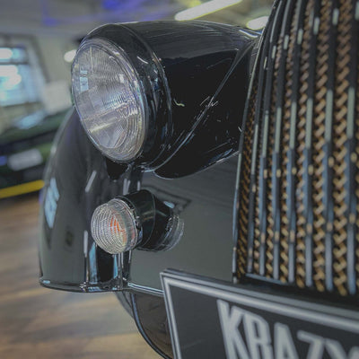Close-up of a car's headlight and front bumper with a textured pattern.