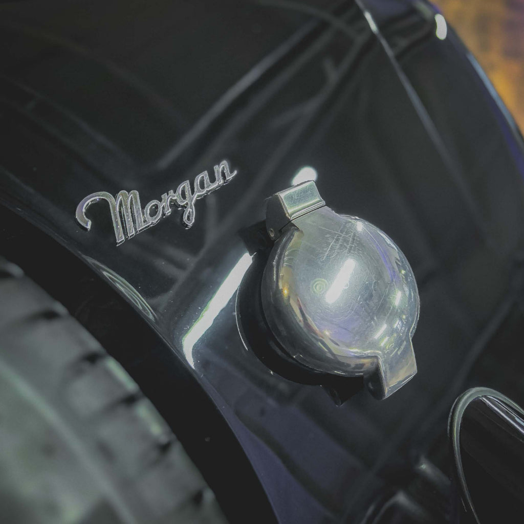 Close-up of a Morgan car emblem on a black surface.