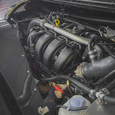 Car engine compartment with various components and hoses.