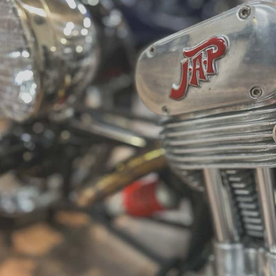 Close-up of a motorcycle with a prominent 'JAP' logo on a blurred background
