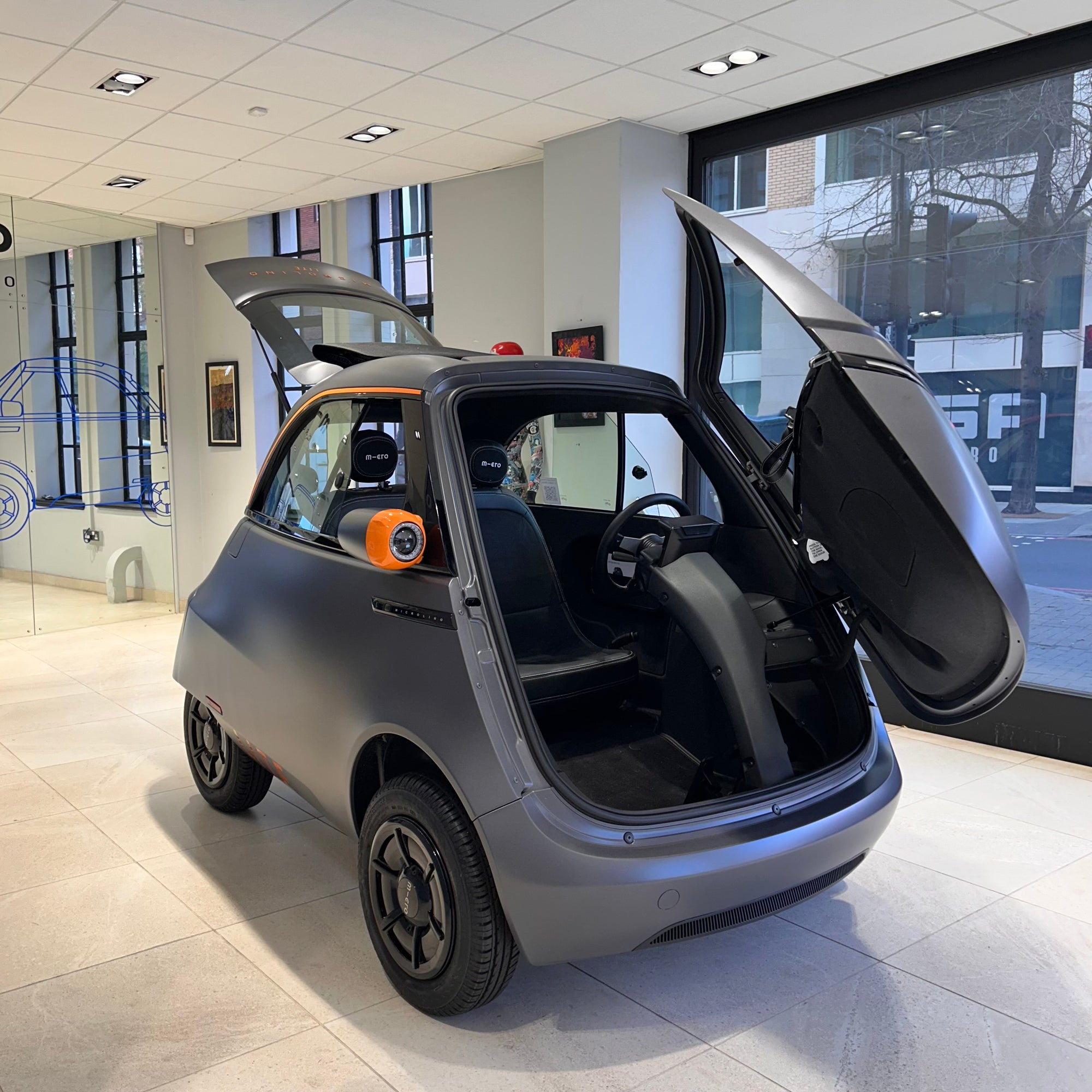 Small electric car with open doors in a showroom setting