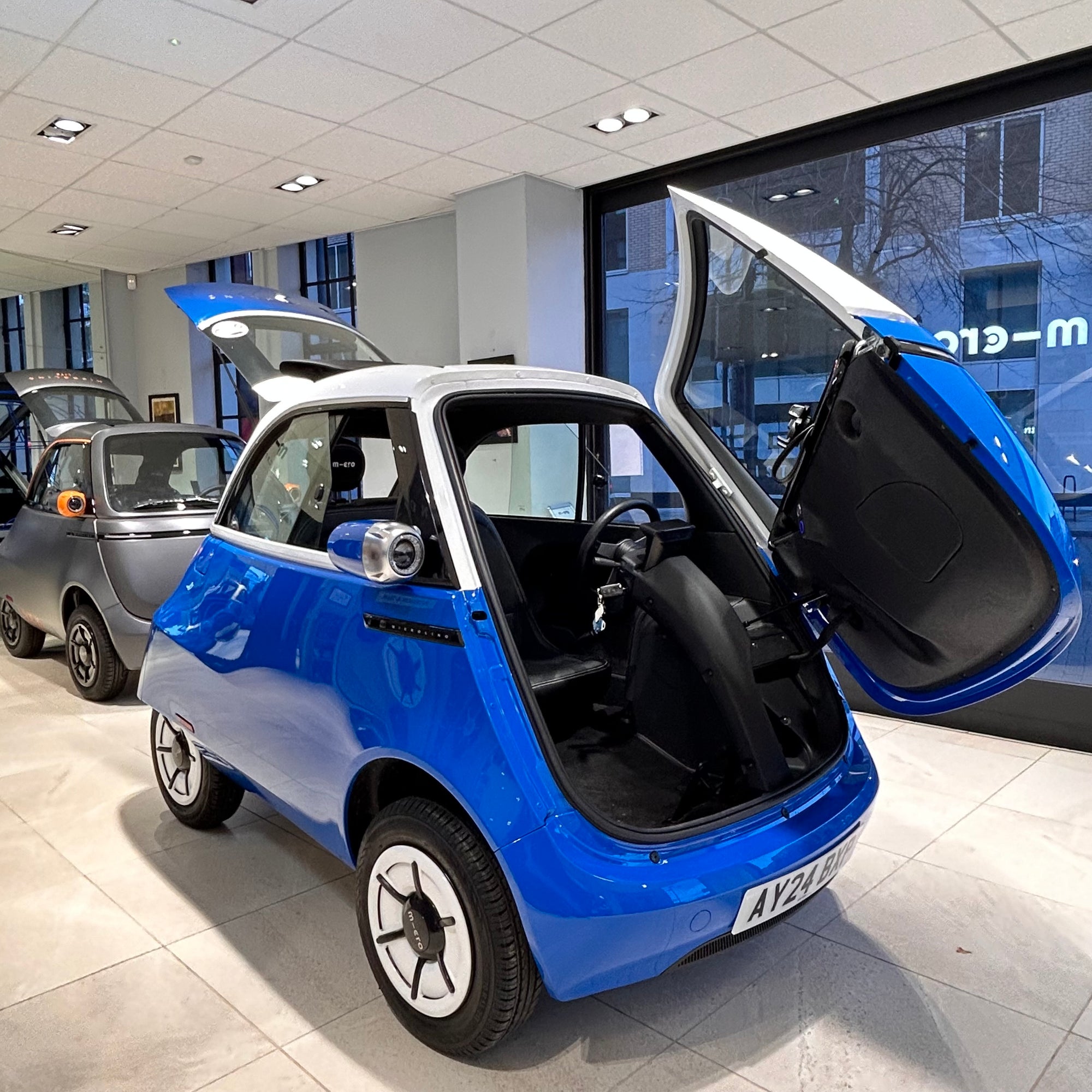 Blue and white electric car with open doors in a showroom