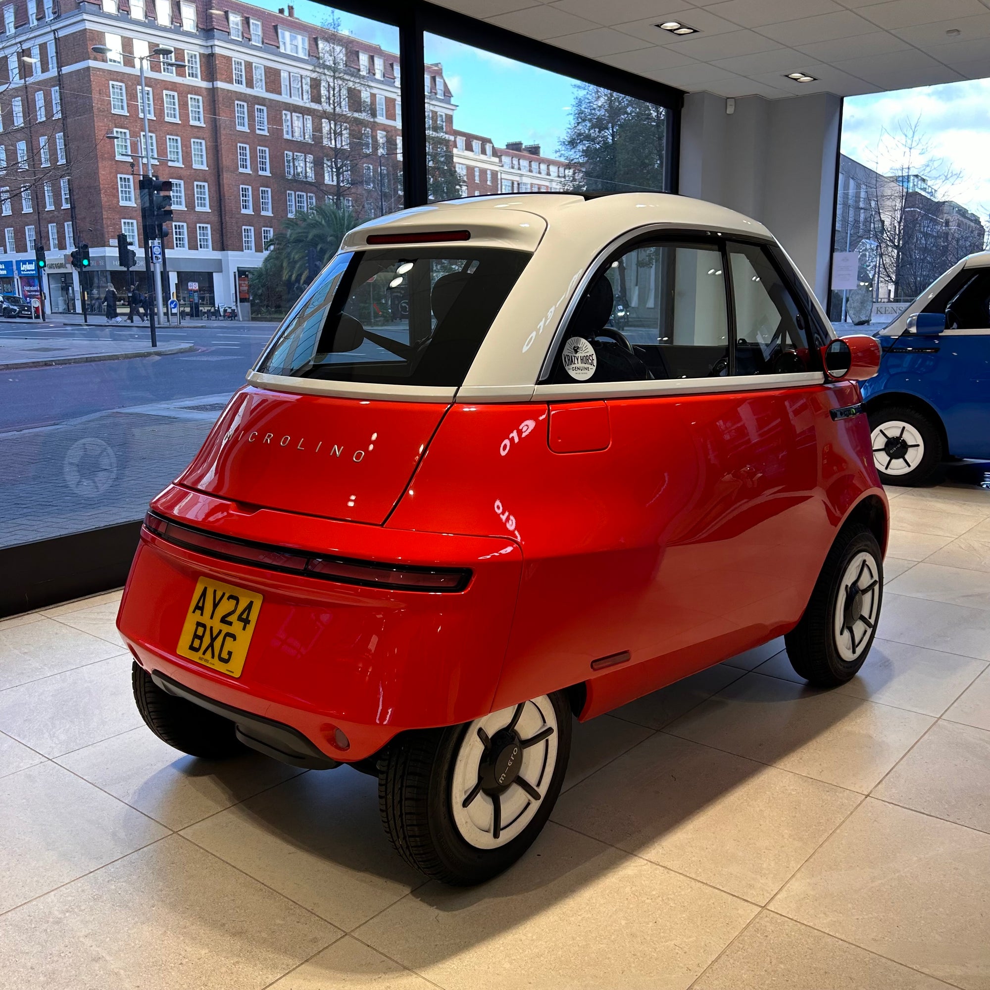 Small red car with a white top in a showroom setting