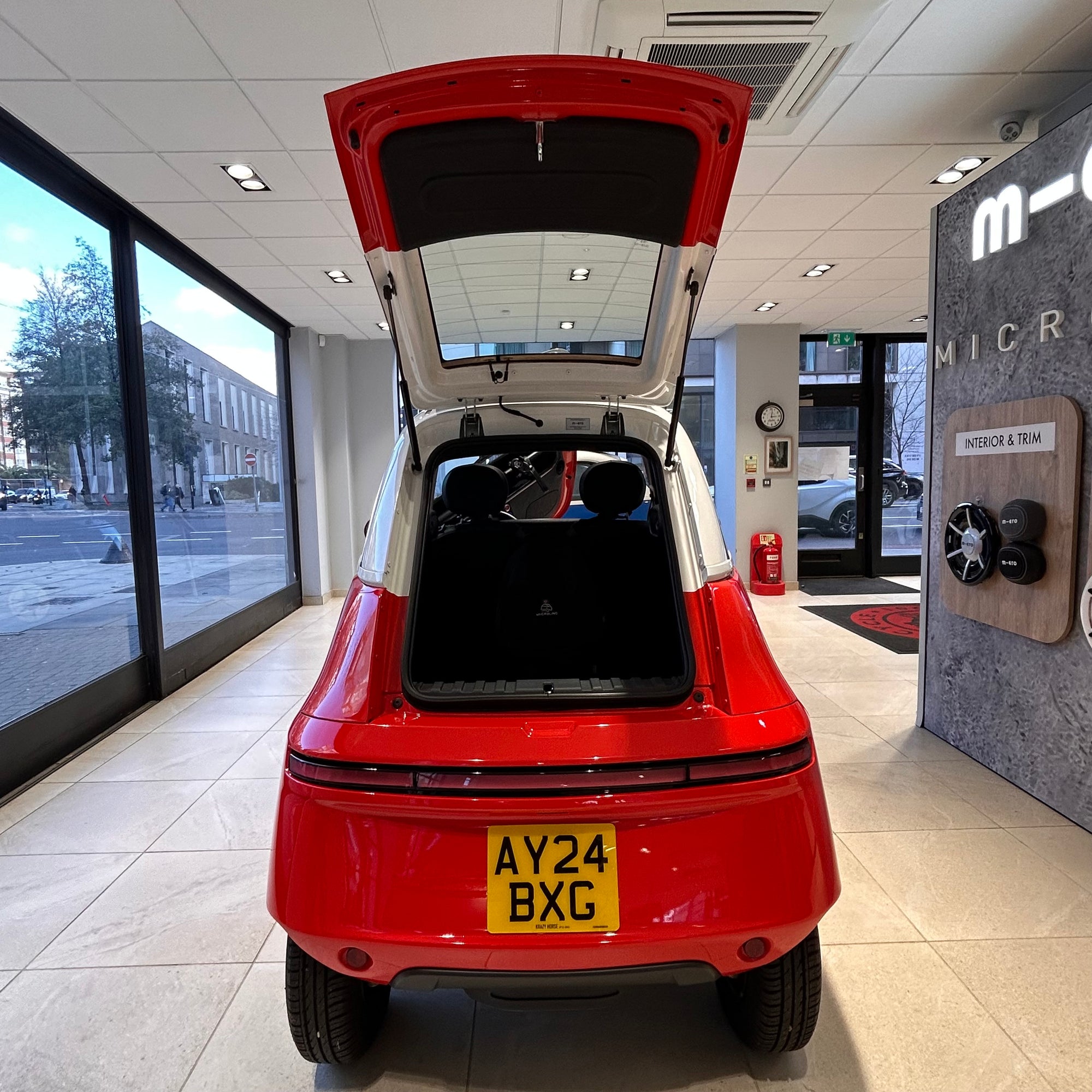 Red car with open trunk in a showroom