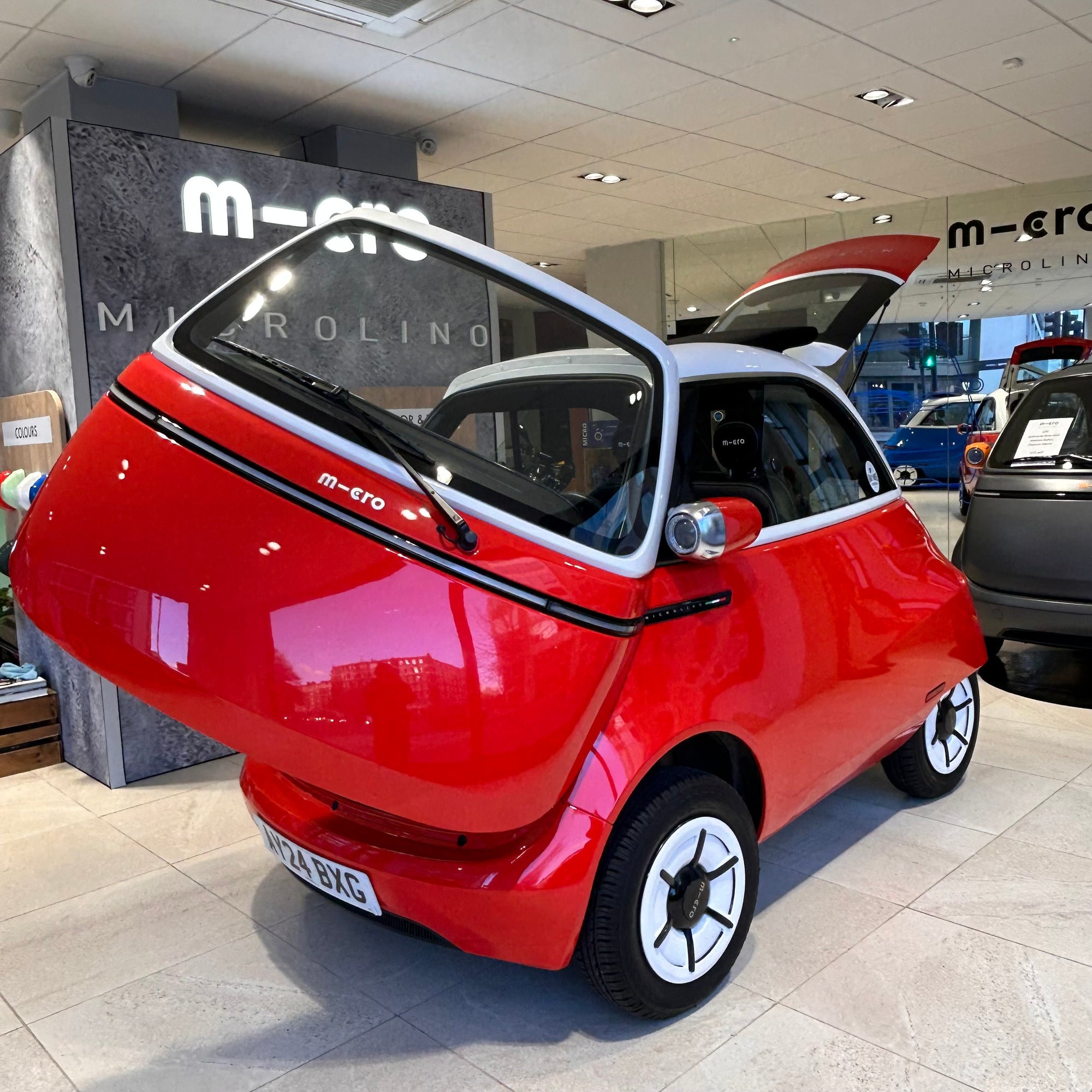 Red microcar with open doors in a showroom setting