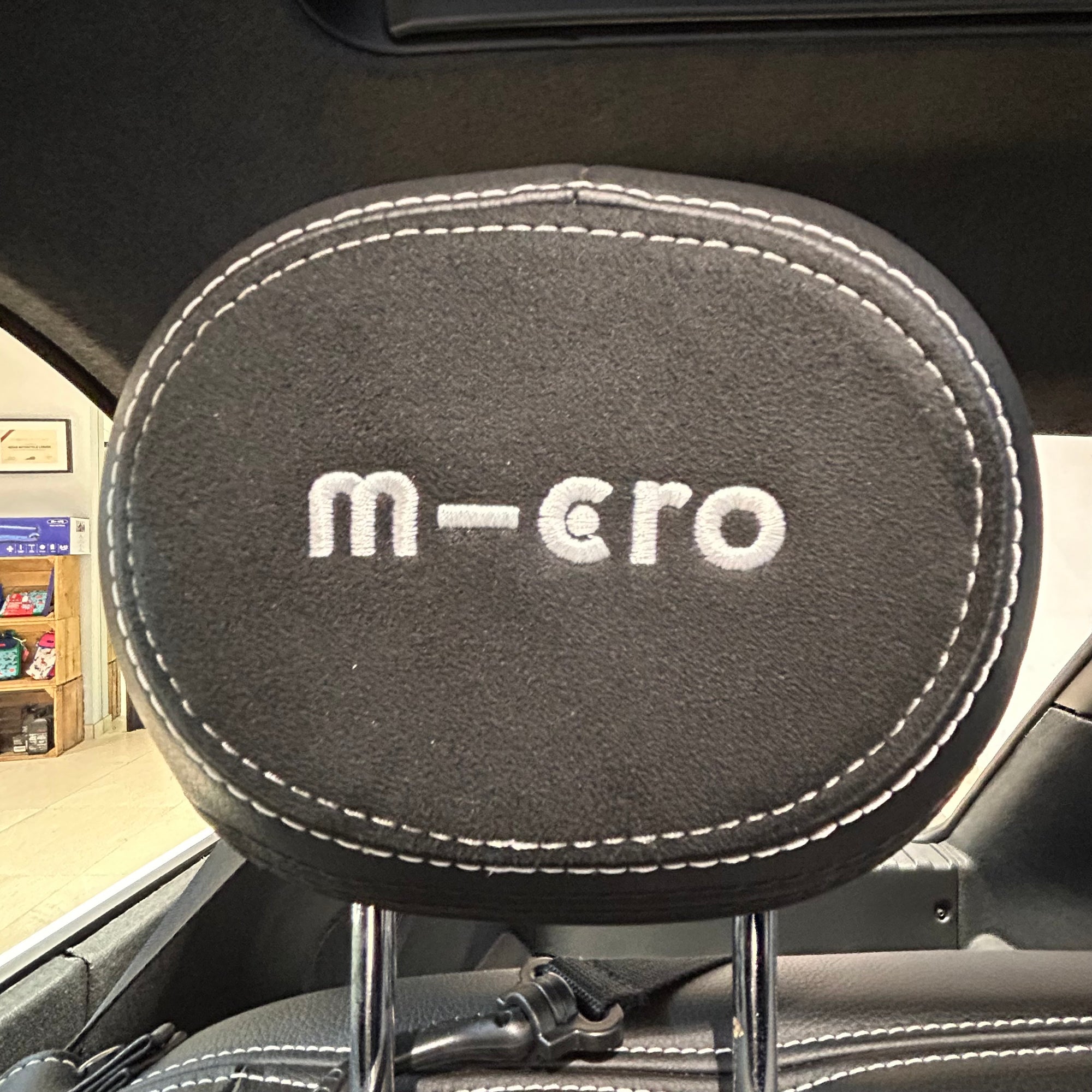 Car headrest cover with 'm-ero' branding inside a vehicle.