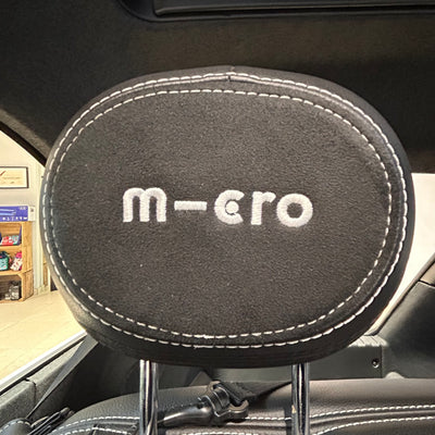 Car headrest cover with 'm-ero' branding inside a vehicle.