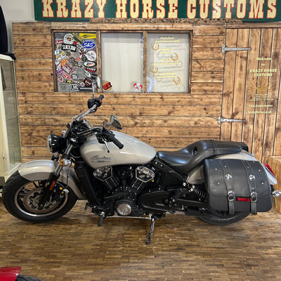 Motorcycle parked in front of a wooden wall with 'Krazy Horse Customs' sign.