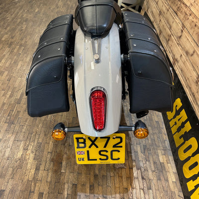 Motorcycle with a visible license plate on a wooden floor