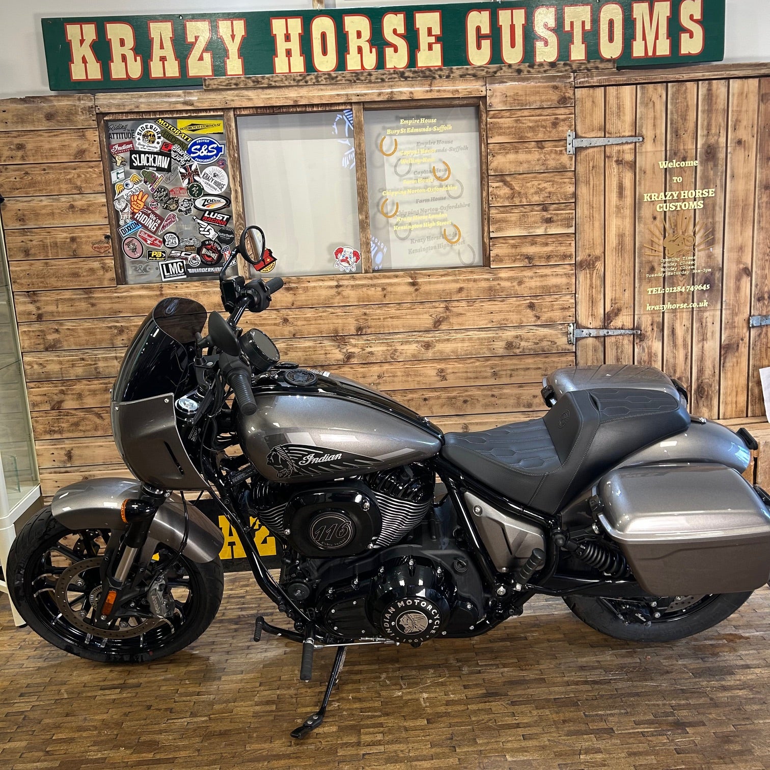 Motorcycle in front of a wooden wall with 'Krazy Horse Customs' sign