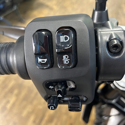 Close-up of a motorcycle handlebar control panel with buttons and switches.