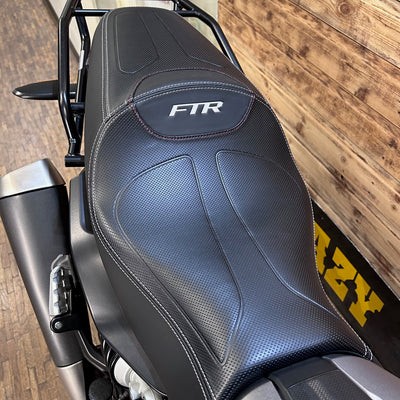 Motorcycle seat with 'FTR' branding on a wooden floor