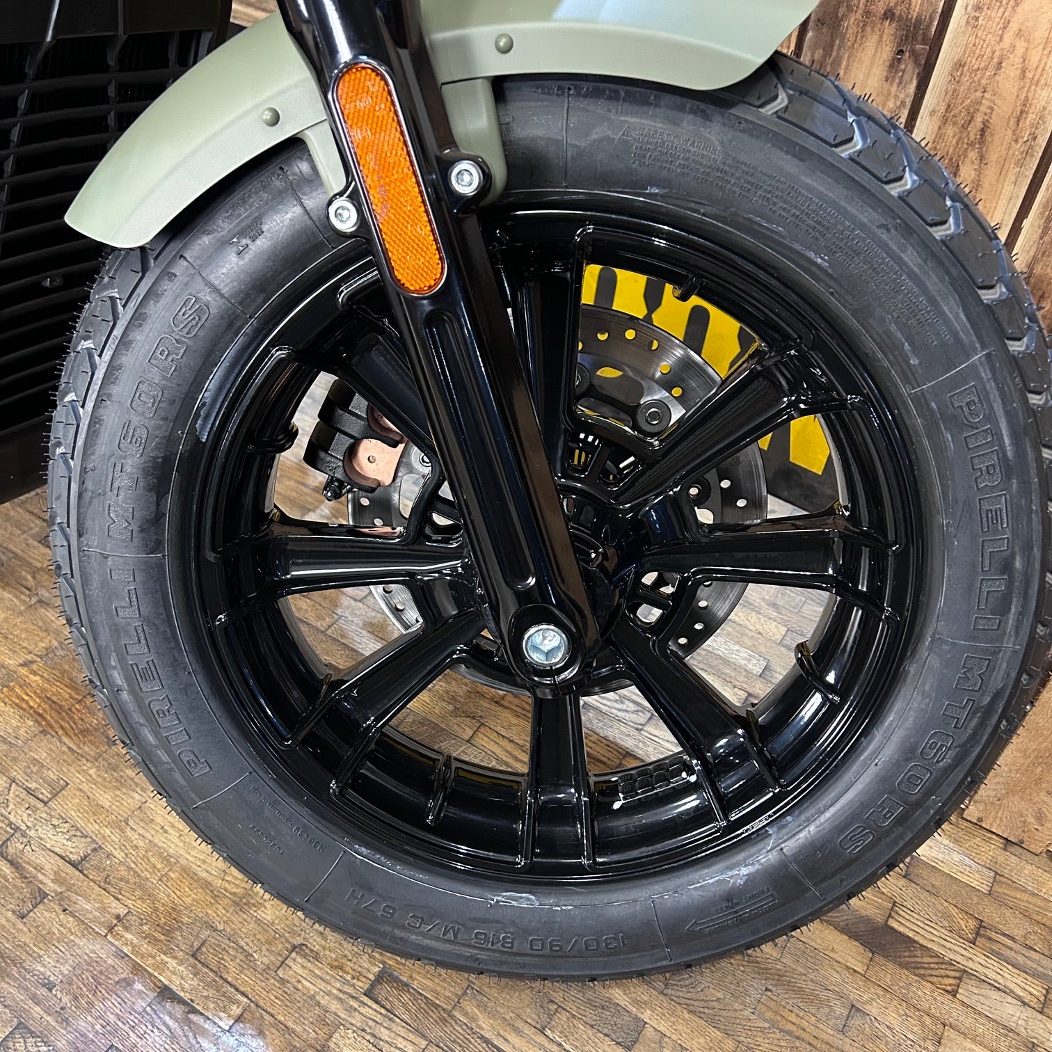 Close-up of a motorcycle wheel with a wooden floor background